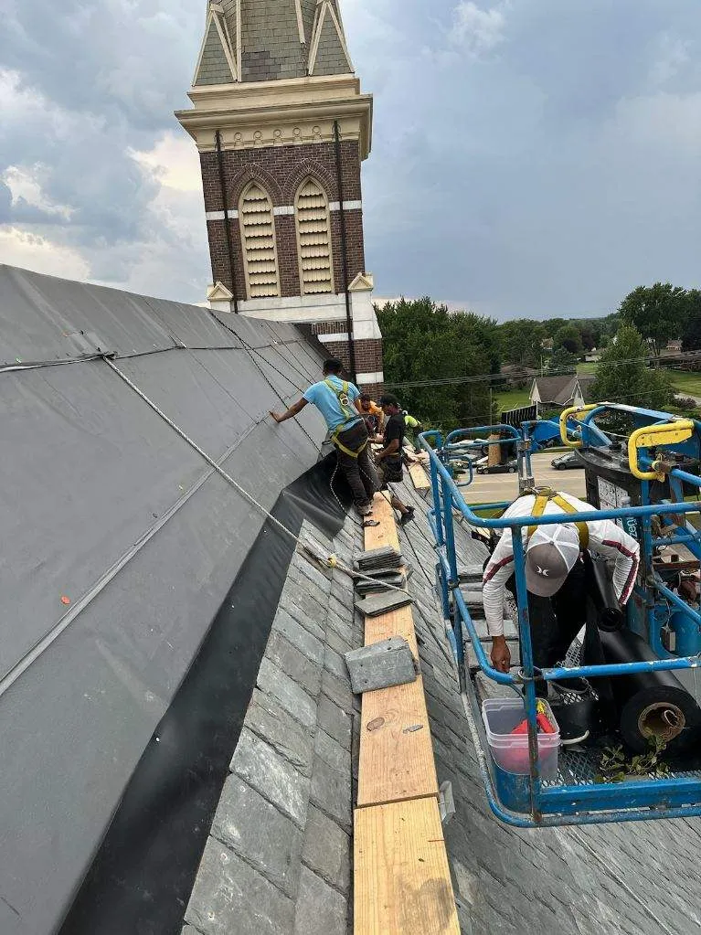 DG Builders crew installing slate roof on historic church from scaffolding