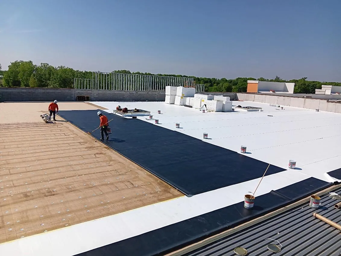 DG Builders crew rolling out flat roof membrane on commercial building in Genesee County Michigan
