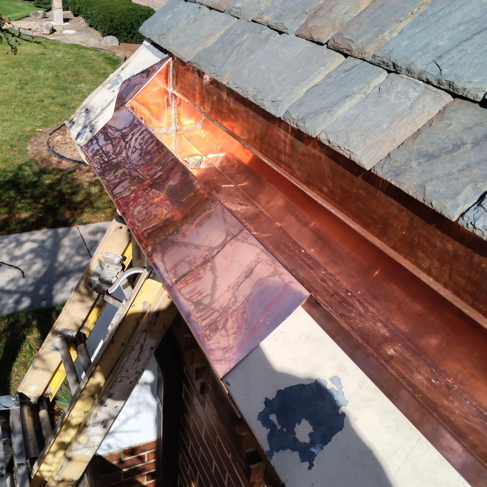 Close-up of copper gutter on slate church roof by DG Builders
